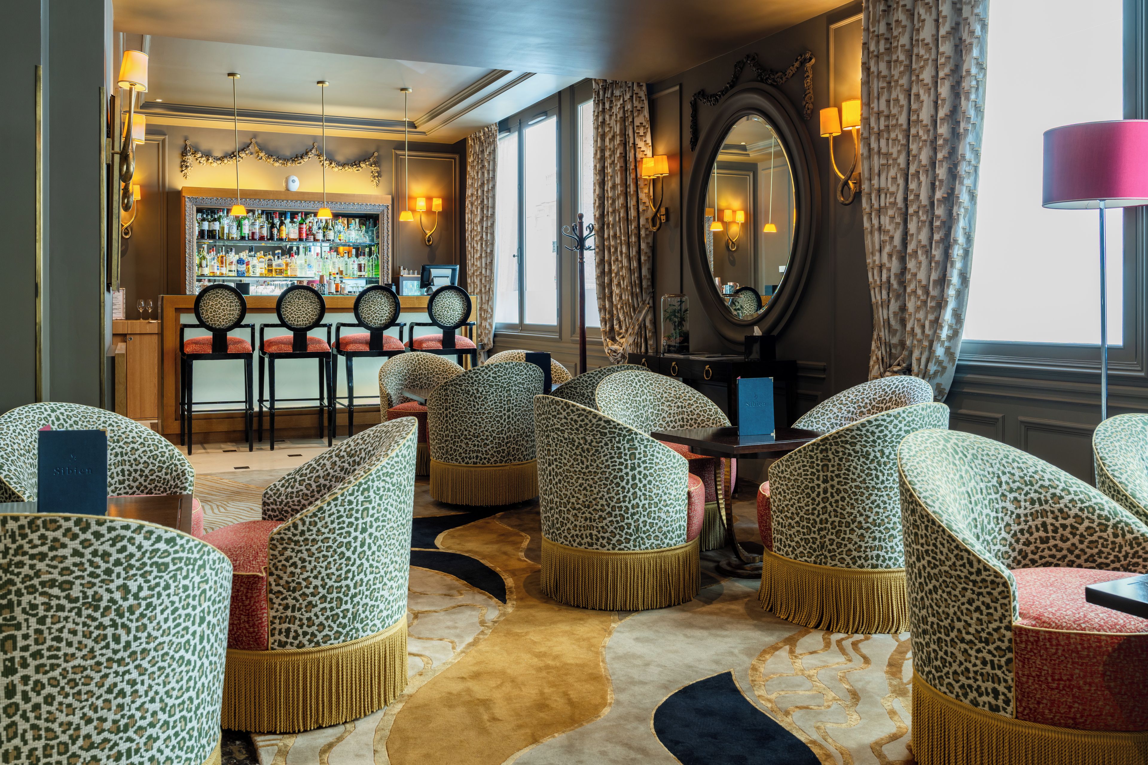 A bar area with a variety of liquor bottles, a seating area with patterned chairs, and a large mirror.