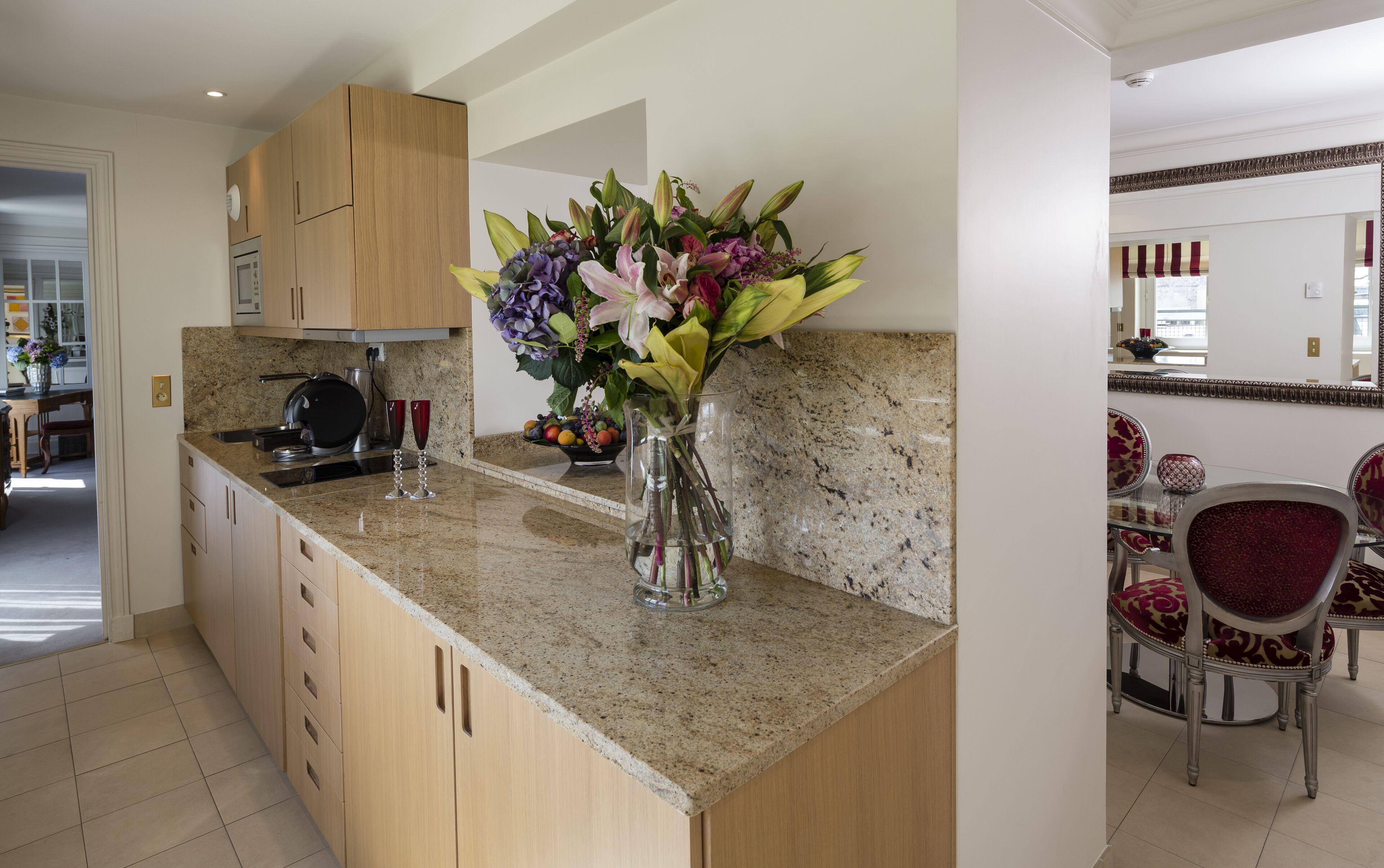 Eine Küche mit Holdelementen, einer Arbeitsplatte aus Granit und einer Vase mit Blumen.