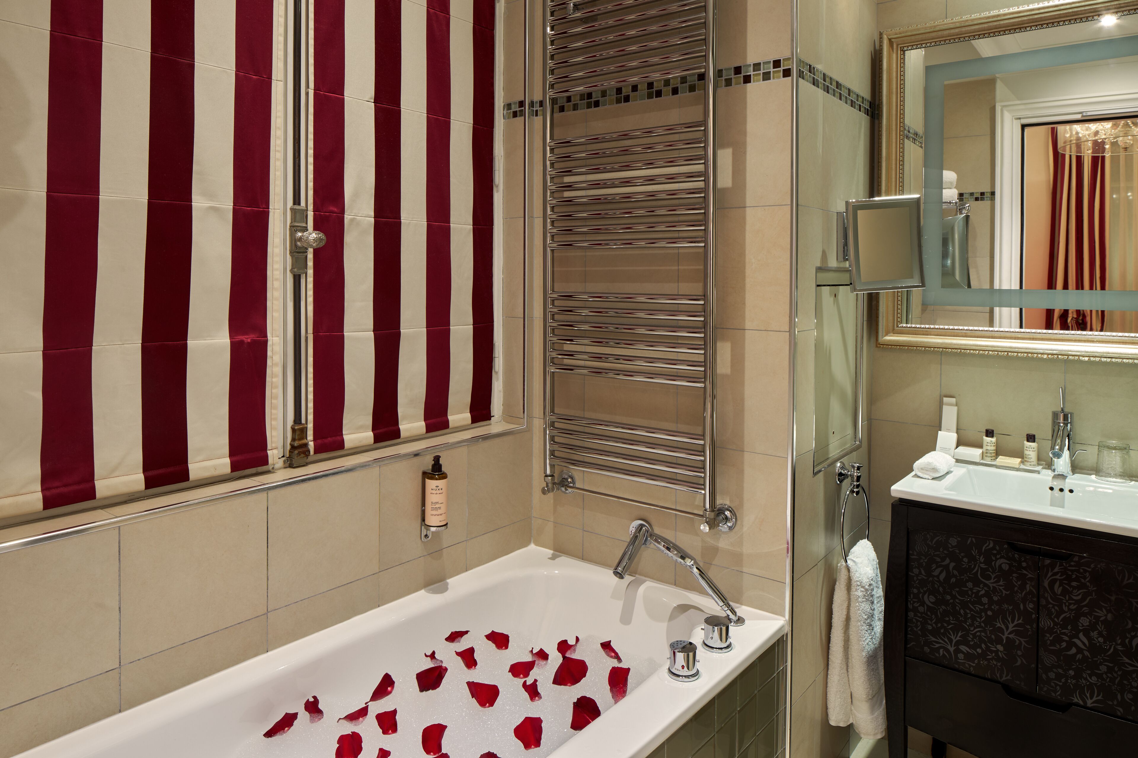 A bathroom with a bathtub, a mirror, a towel rack, and a shower area.