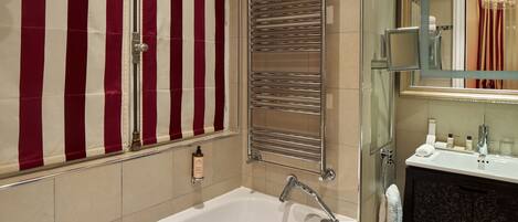 Un baño con bañera, espejo, toallero y zona de ducha.