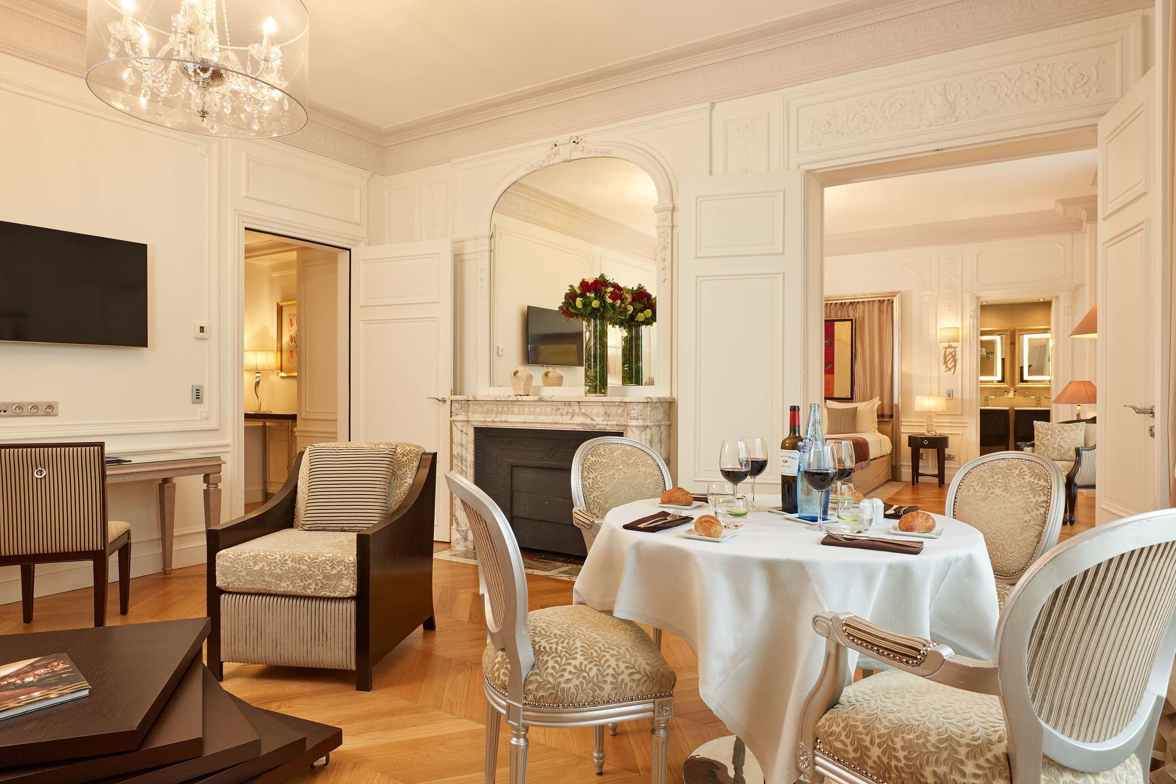 A dining area with a fireplace, a television mounted on the wall, and a table set for a meal.