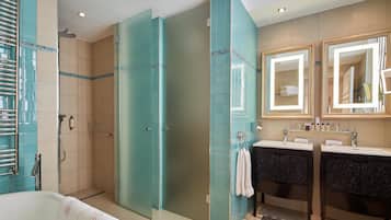 A modern bathroom with a glass-enclosed shower, two sinks with dark cabinets, and a large mirror above the sinks.