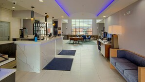A modern hotel lobby with a reception desk, seating area, and a view of the outdoors. - Homewood Suites by Hilton South Bend Notre Dame Area (South Bend)