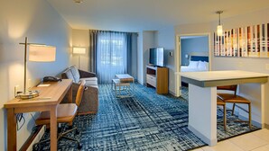 A hotel room with a desk, chair, sofa, TV, and a small kitchenette. - Homewood Suites by Hilton South Bend Notre Dame Area (South Bend)