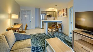 A modern hotel room with a kitchenette, a dining area, a living room with a sofa and a TV. - Homewood Suites by Hilton South Bend Notre Dame Area (South Bend)