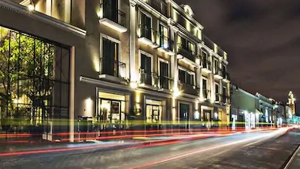 A nighttime view of a row of buildings with illuminated windows and a street with light trails. - Hotel Nacional Merida (Mérida)