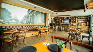 A restaurant with wooden furniture, a large window, and a bar area. - Hotel Nacional Merida (Mérida)