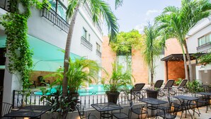 A patio with outdoor seating, a pool, and surrounding greenery. - Hotel Nacional Merida (Mérida)