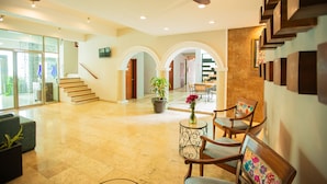 A spacious lobby with a high ceiling, a ceiling fan, a staircase, and a seating area with chairs and a table. - Hotel Nacional Merida (Mérida)