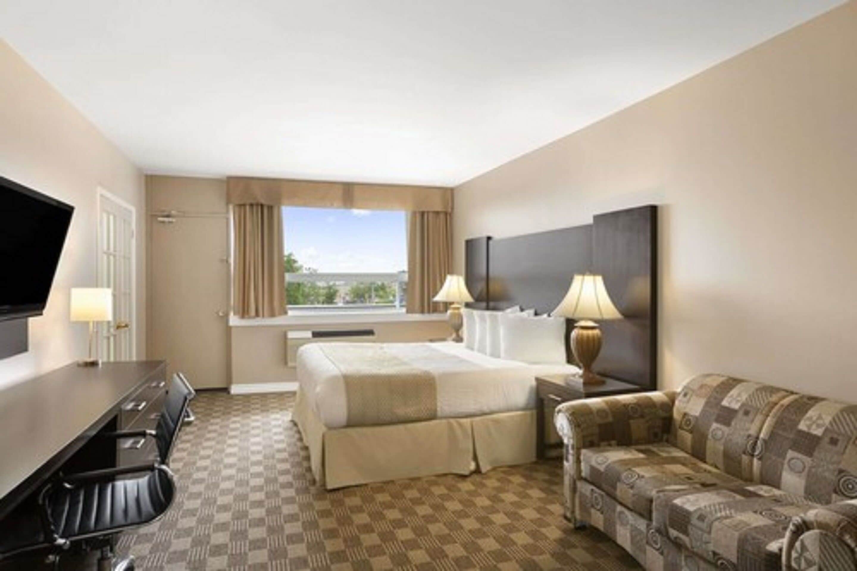 Een hotelkamer met een bed, een slaapbank, een bureau en een televisie.