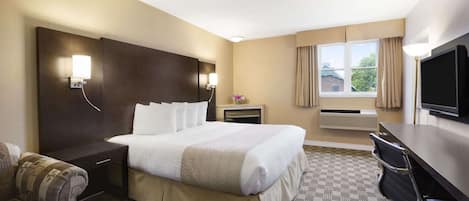 Habitación de hotel con una cama grande, un escritorio, una silla, un televisor y una ventana con cortinas.