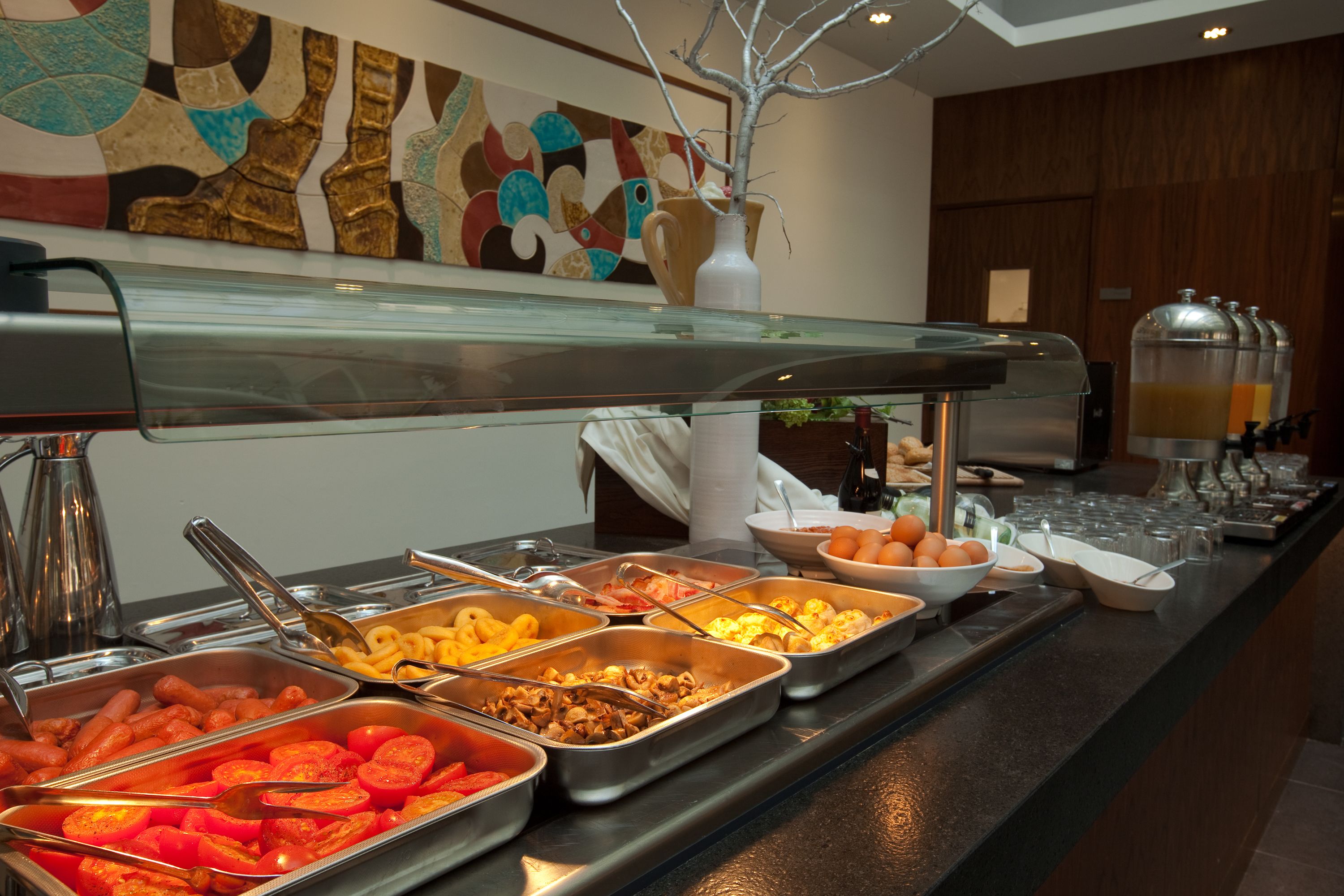 A buffet with various food items and a decorative vase.