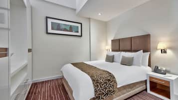 A hotel room with a large bed, bedside lamps, a nightstand with a phone, and a framed picture on the wall.