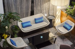 Una sala de estar moderna con un sofá, dos sillones, una mesa de centro y una lámpara.