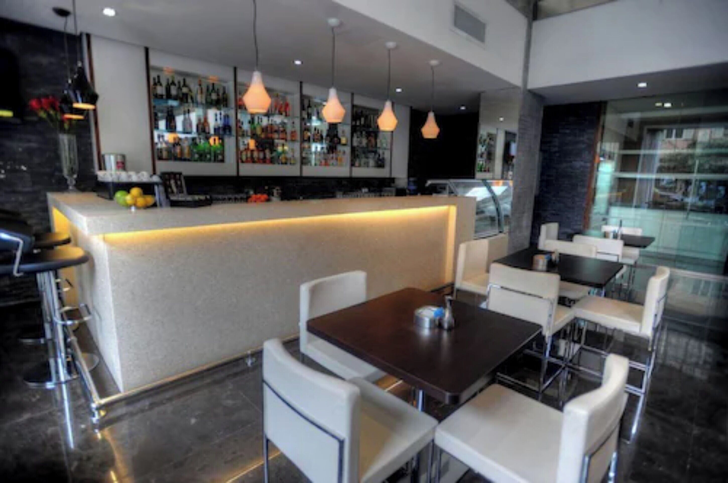 Un bar moderno con barra, asientos e iluminación colgante.