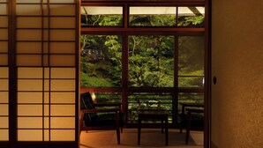 A traditional Japanese room with tatami flooring, a sliding shoji screen, and a view of a lush garden. - Negiya Ryofukaku (Kobe)