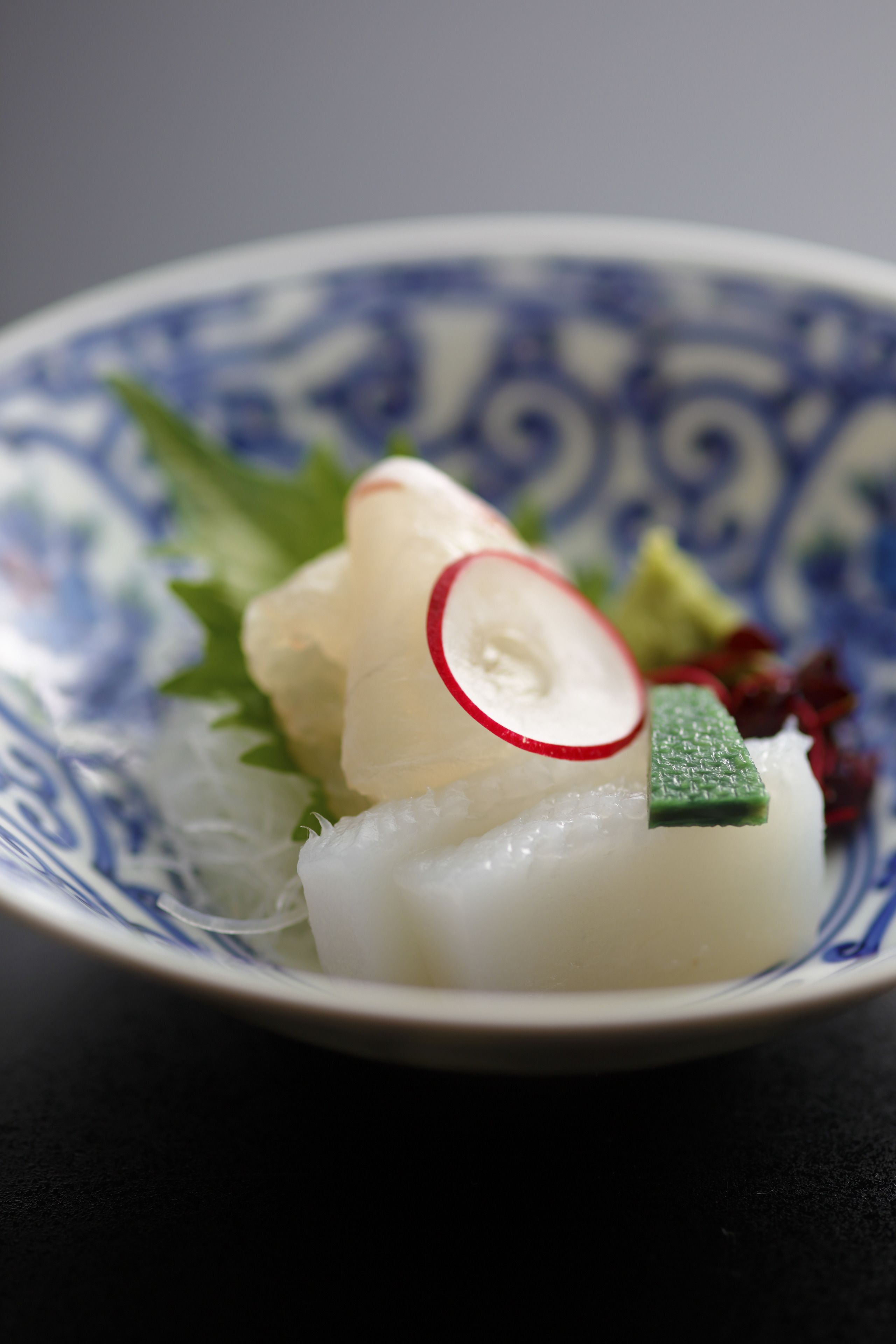 A bowl of sashimi with a decorative blue and white pattern.