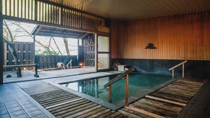 A modern indoor pool area with wooden flooring and a glass door leading outside. - Negiya Ryofukaku (Kobe)