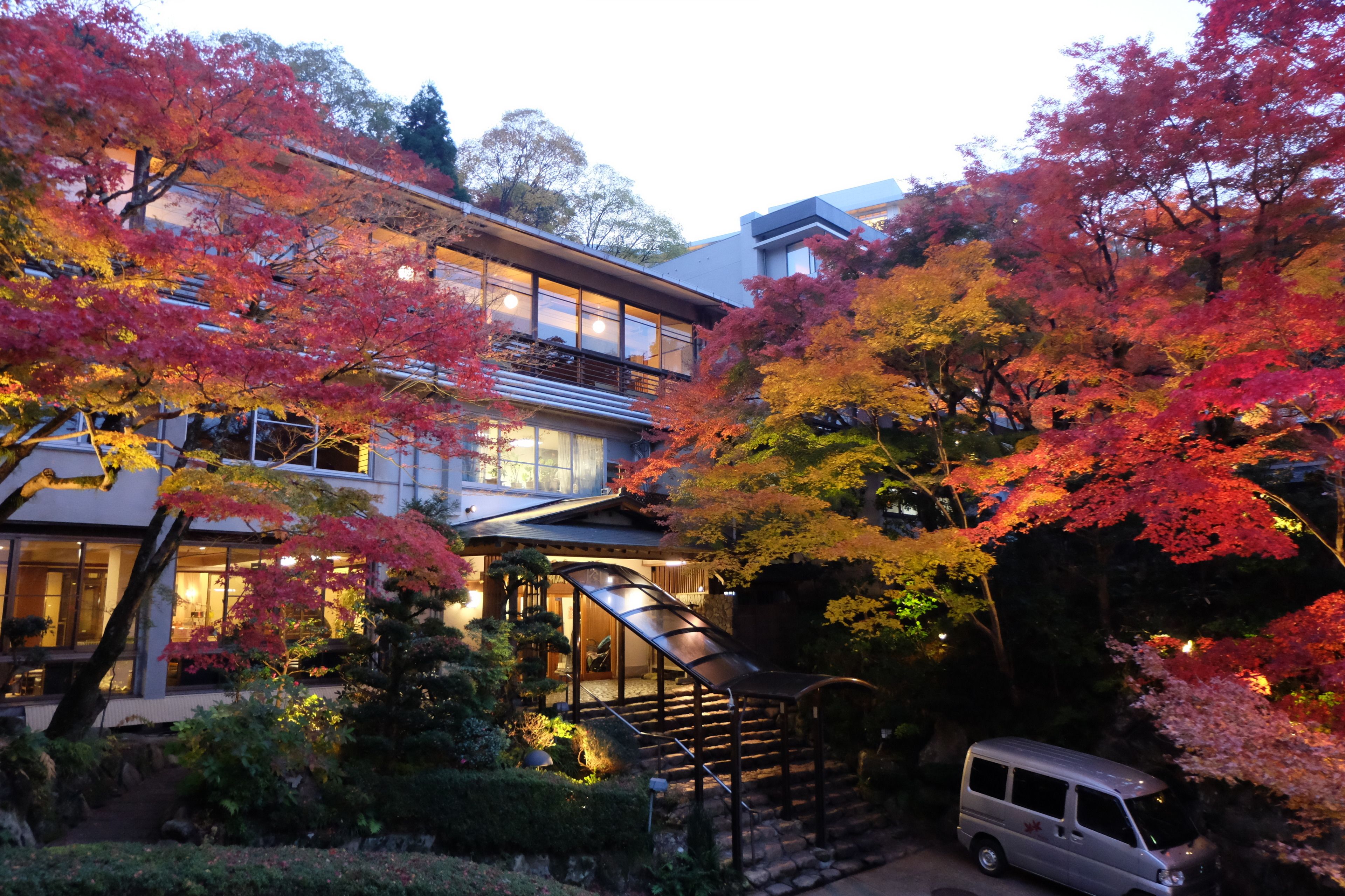 A multi-story building with a modern architectural design, surrounded by lush, autumn-colored foliage.