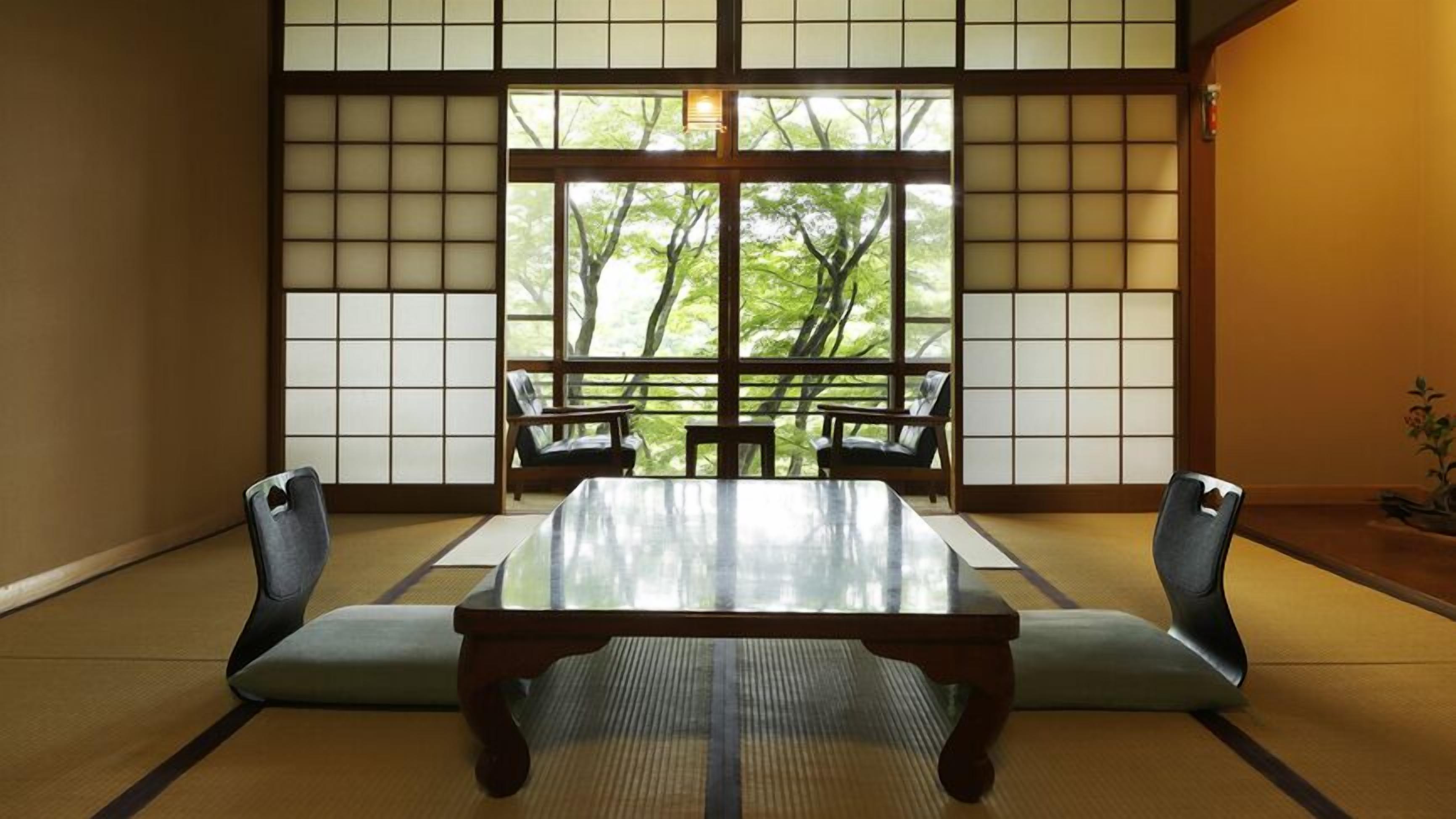 A traditional Japanese room with tatami flooring, a low table, and sliding doors with a view of trees.