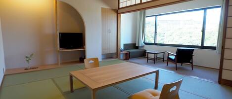 Ett traditionellt japanskt rum med tatamimattor på golvet, ett lågt bord, en soffa och en tv.