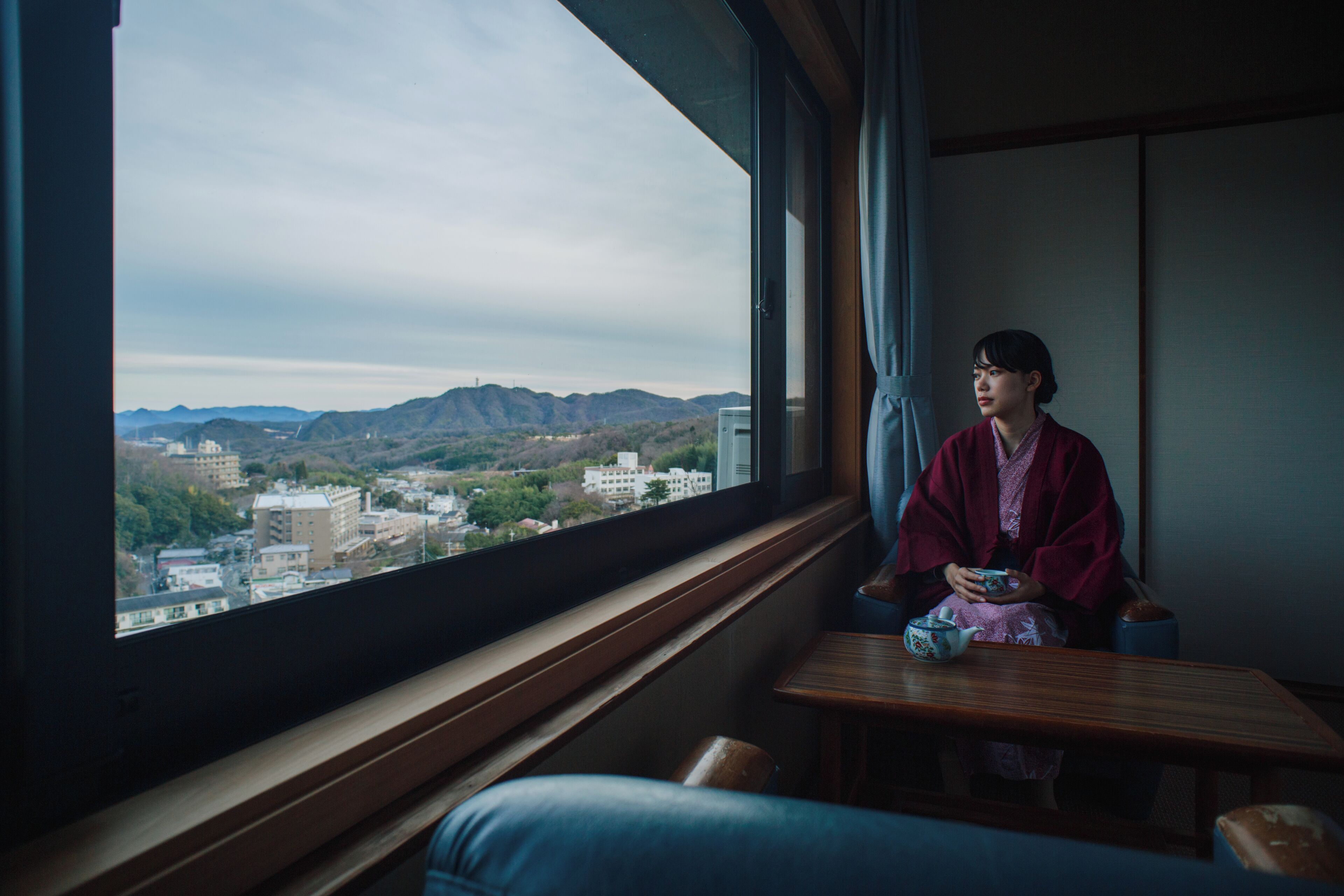 Ein Zimmer mit einem großen Fenster, das einen Blick auf Stadt und Berge bietet.