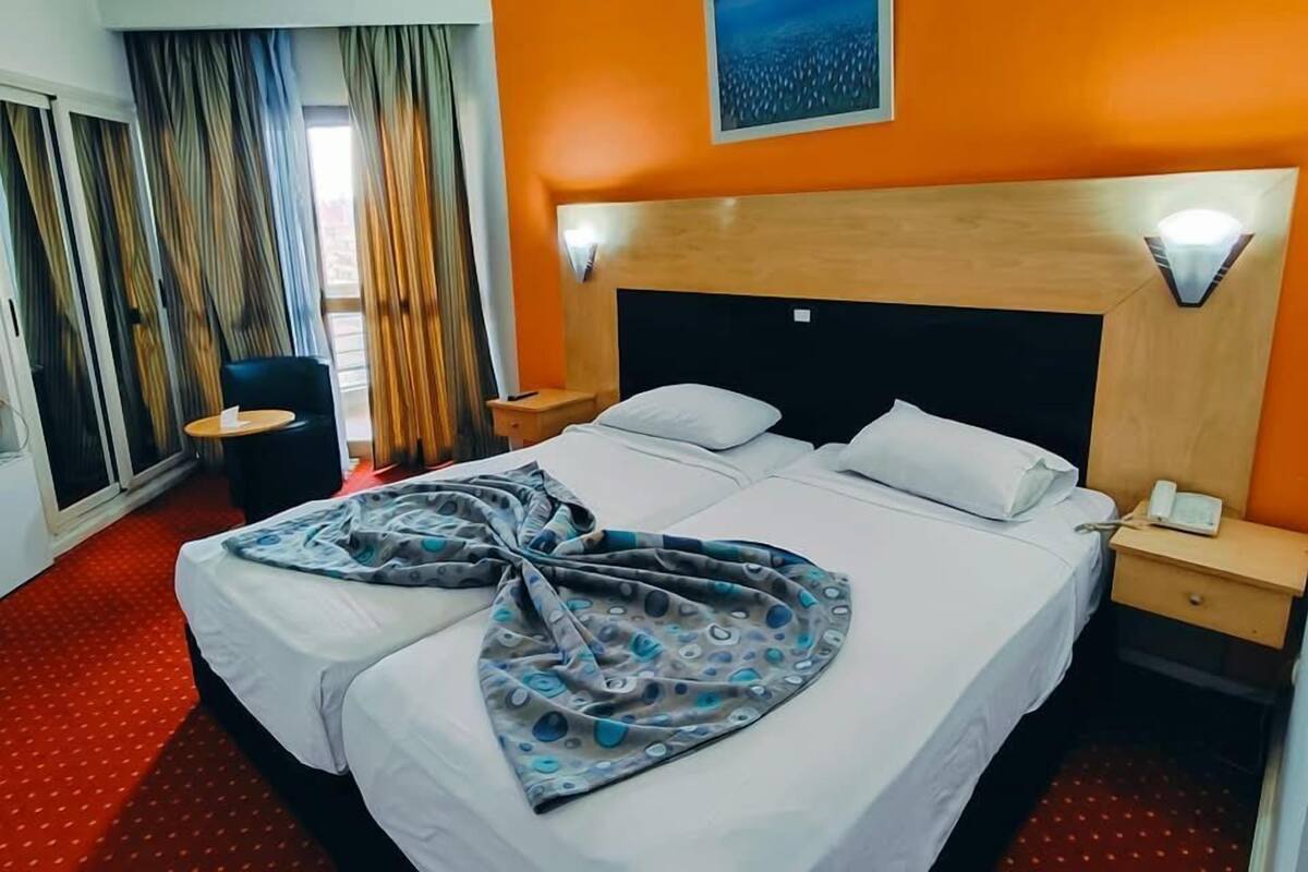 Une chambre d’hôtel avec un lit, une table de chevet, une chaise et un tableau au mur.