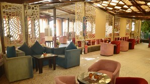 A spacious indoor seating area with multiple chairs and tables, a decorative ceiling, and a view of the outdoors.
