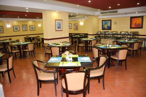A spacious dining area with multiple tables and chairs, arranged in a grid pattern.