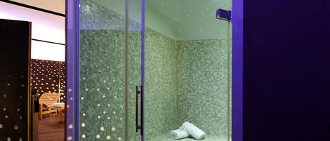 A glass-enclosed shower room with a tiled floor and a bench.