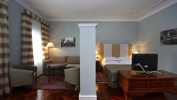 Una camera d'albergo con un letto, una scrivania, una sedia, un divano, un tavolino e una lampada.