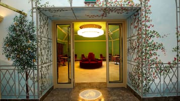 Un hall d’hôtel agrémenté d’un mur végétal, de sièges rouges et d’un grand lustre.
