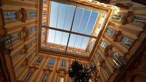 A high-ceilinged atrium with a large skylight, ornate architectural details, and multiple balconies. - Grand Hotel Piazza Borsa (Palermo)