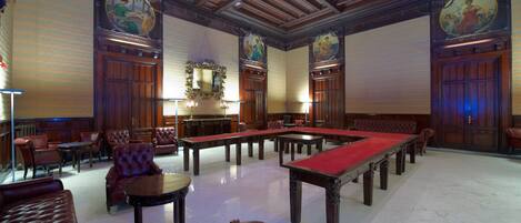 A spacious room with a pool table, leather seating, and ornate wooden paneling.
