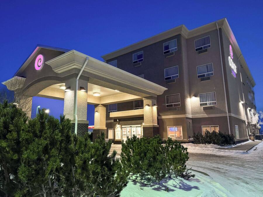 A multi-story hotel with a covered entrance, outdoor seating area, and a parking lot.