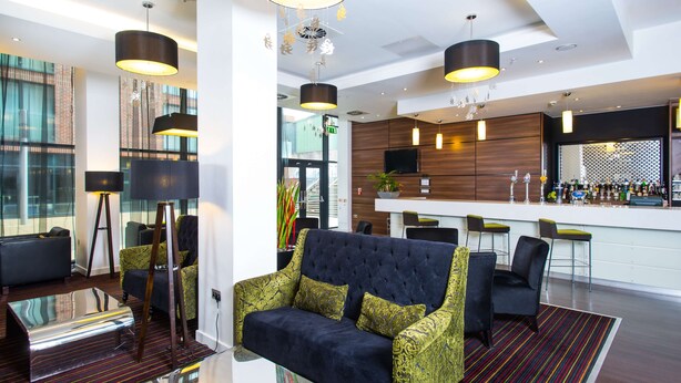Un moderno vestíbulo de hotel con zona de bar, arreglos de asientos y un amplio ventanal que proporciona luz natural.