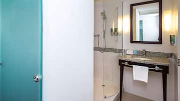 Un baño con cabina de ducha de vidrio, lavabo de encimera de granito y un espejo grande.