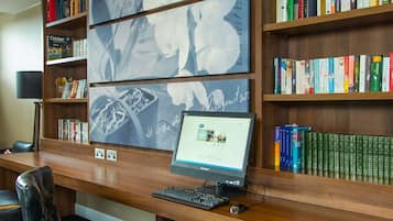 A library with bookshelves, a desk with a computer, and leather chairs.