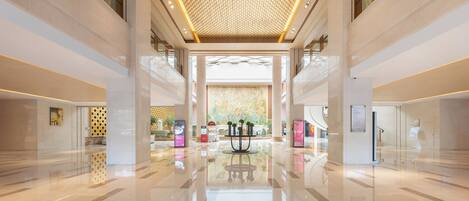 A spacious lobby with a high ceiling, polished floors, and a central decorative column.