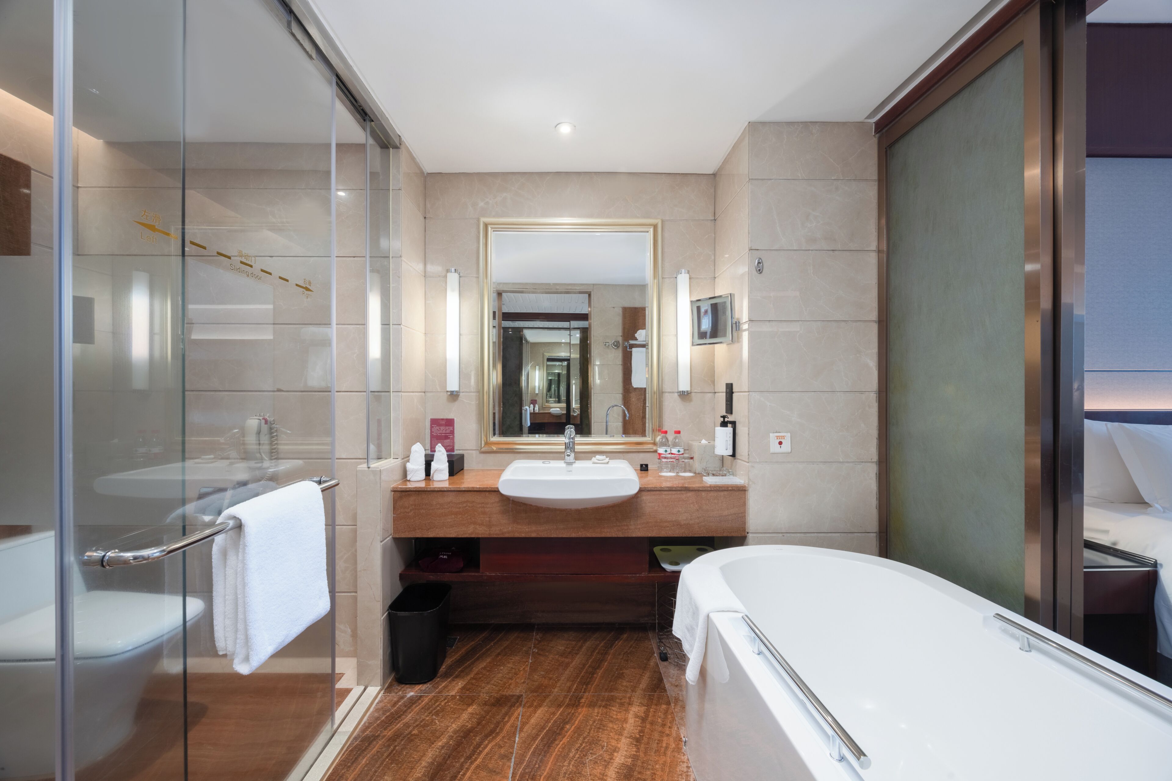A modern bathroom with a glass shower enclosure, a large mirror, a sink, and a bathtub.