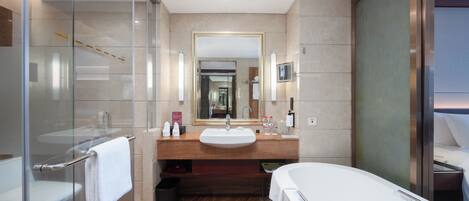 A modern bathroom with a glass shower enclosure, a large mirror, a sink, and a bathtub.