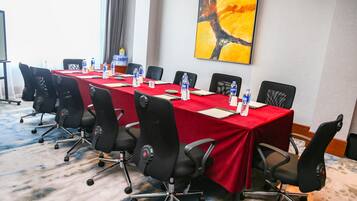 A conference room with a long table, black chairs, water bottles, and a red tablecloth.