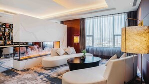 A modern living room with a fireplace, comfortable seating, a bookshelf, and a large window with curtains. - Marco Polo Jinjiang (Quanzhou)