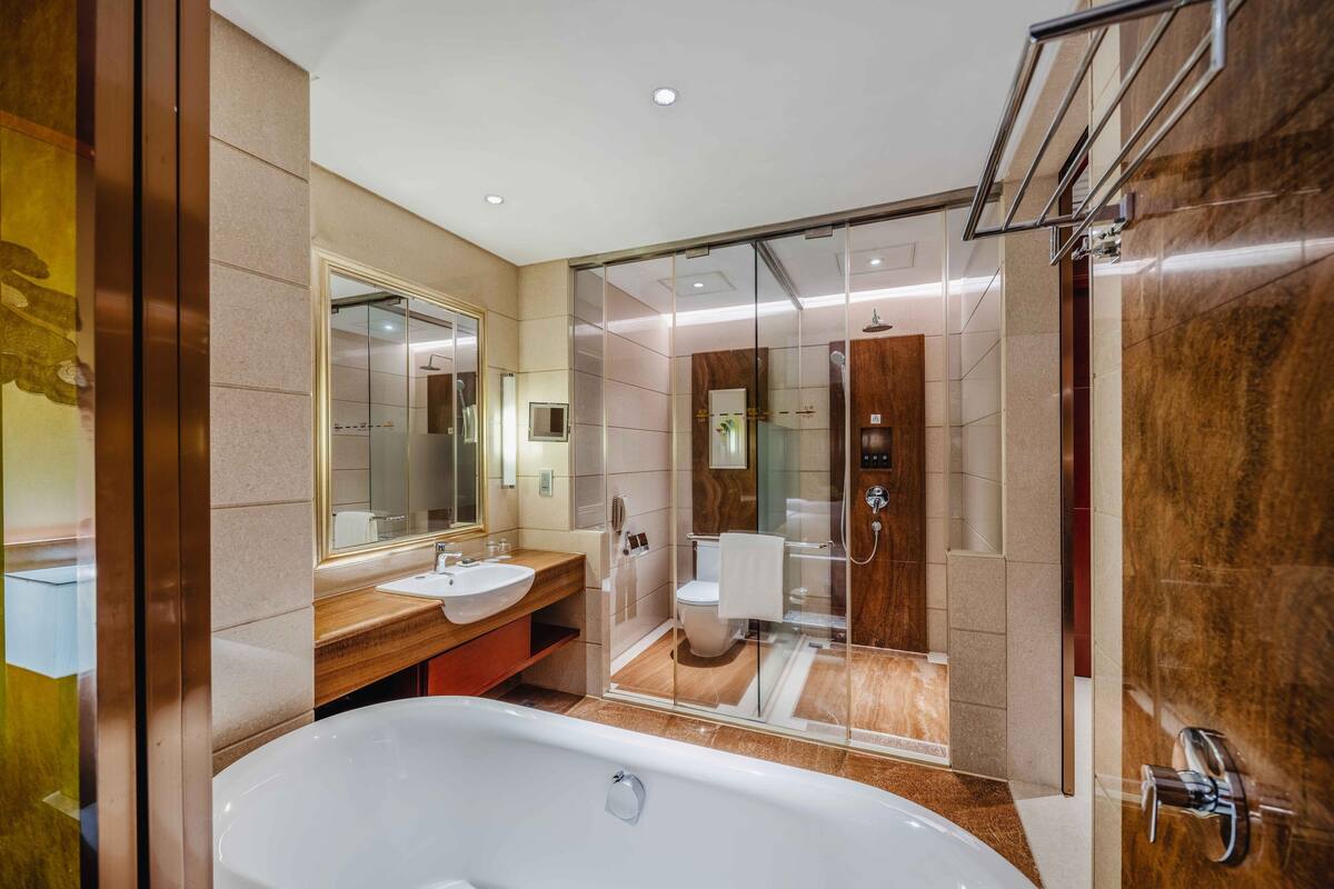 A modern bathroom with a large bathtub, a vanity with a mirror, and a glass-enclosed shower area.