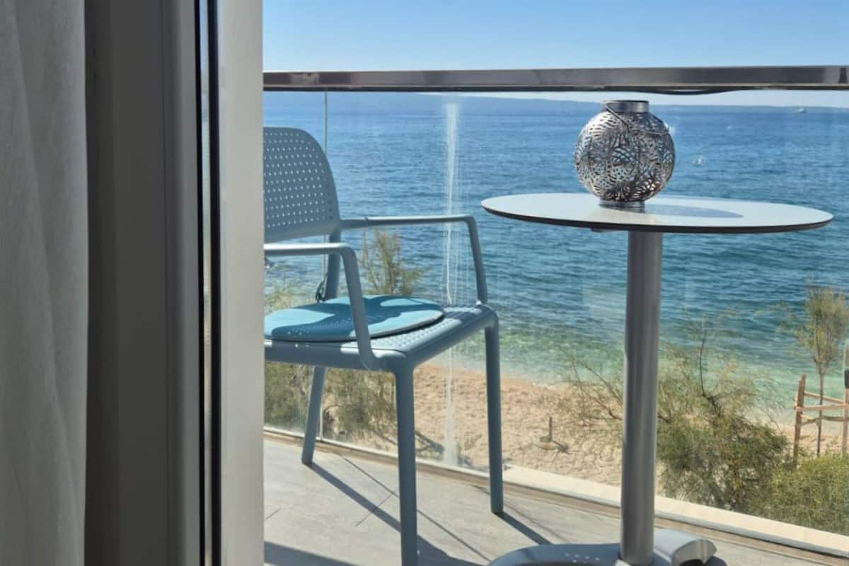 Un balcón con mesa y sillas, con vistas a la playa y al mar.