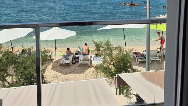 A beach view from a balcony with umbrellas and lounge chairs. - Villa Zanic (Podstrana)