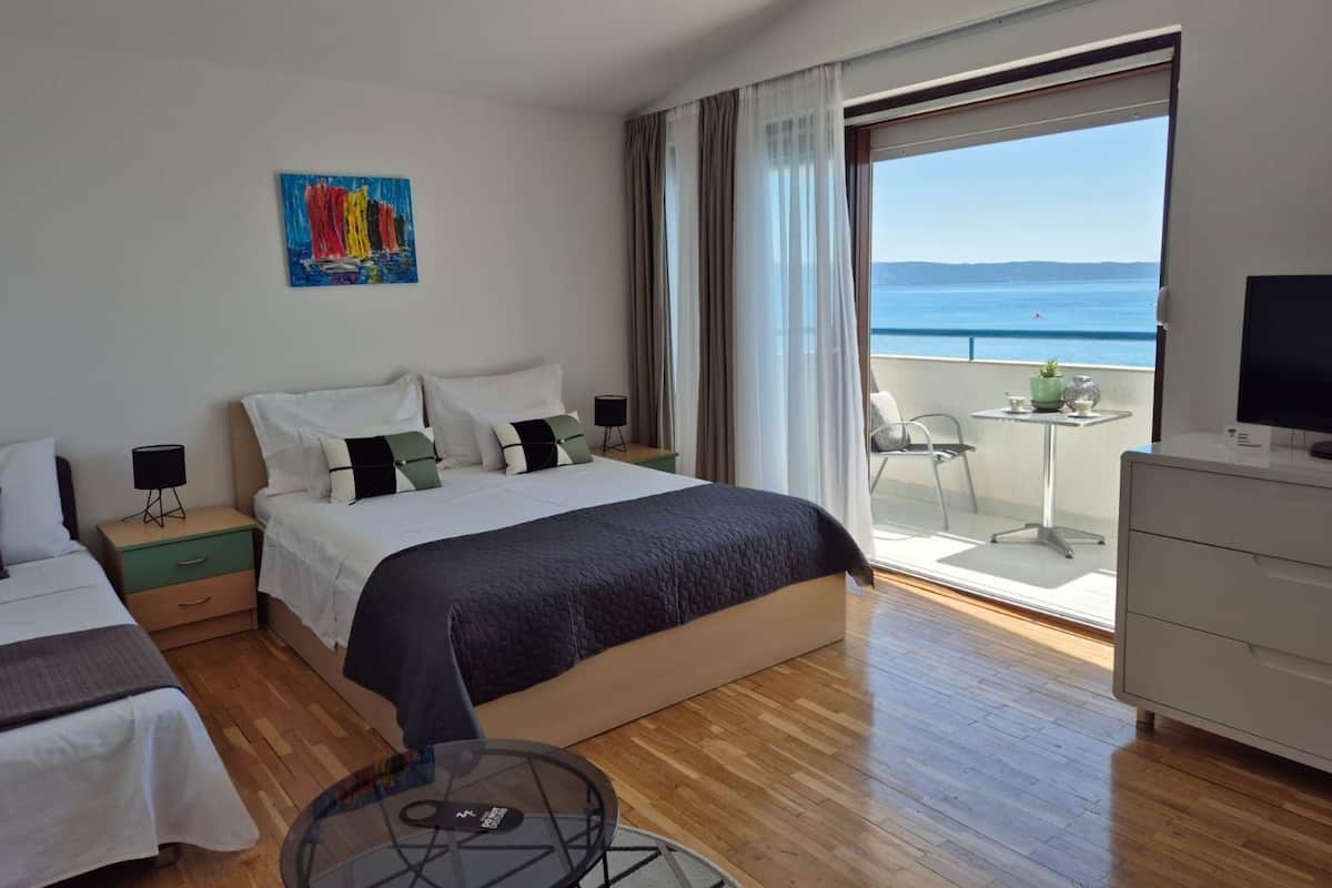 Una habitación de hotel con cama, escritorio, silla, televisor y balcón con vista al mar.