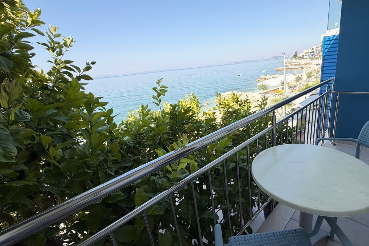 Un balcón con vista al mar, una mesa redonda y dos sillas.