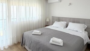 Una habitación de hotel con cama, cortinas, aire acondicionado y una mesita de noche.