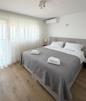 Una habitación de hotel con cama, cortinas, aire acondicionado y una mesita de noche.